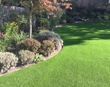 Artificial lawn around bushy flowerbeds and borders