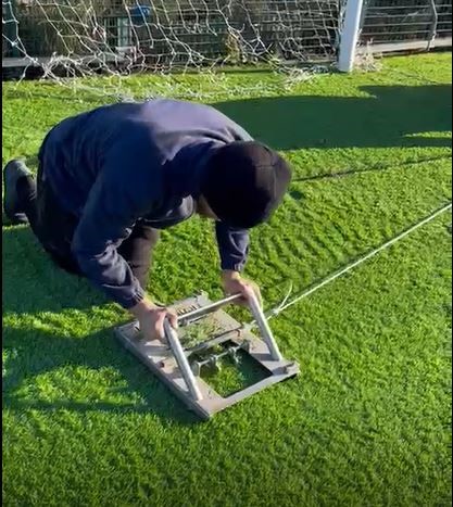 cutting markings into artificial grass football pitch