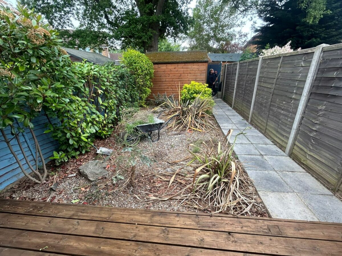Before image of a garden which is overgrown with dirt and gravel.